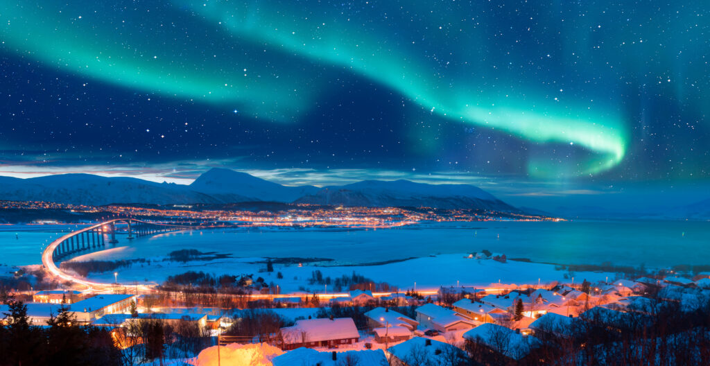 Aurora boreal en el cielo sobre Tromsø, con el puente Sandnessundet — Tromsø, Noruega.