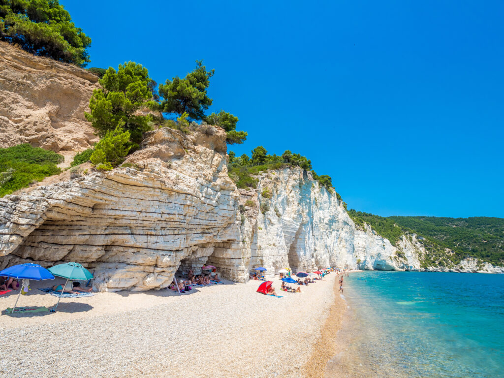 APULIA, IT - 19 de julio de 2018: Pilas de Mattinata Faraglioni y costa de playa de Baia Delle Zagare, Vieste Gargano, Apulia, Italia