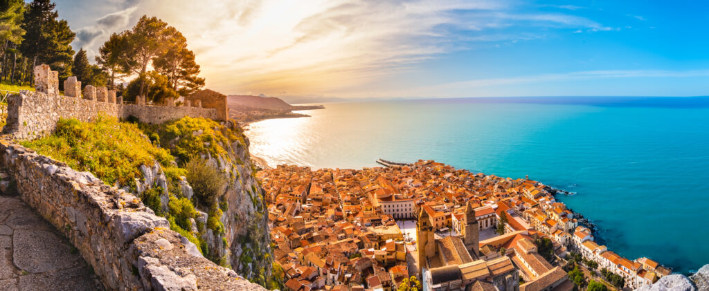 Vista aérea de Cefalú al atardecer. Pueblo medieval en la isla de Sicilia, Italia. Localidad costera con playa de arena, mar, edificios históricos y montañas. Un destino turístico popular en la provincia de Palermo.