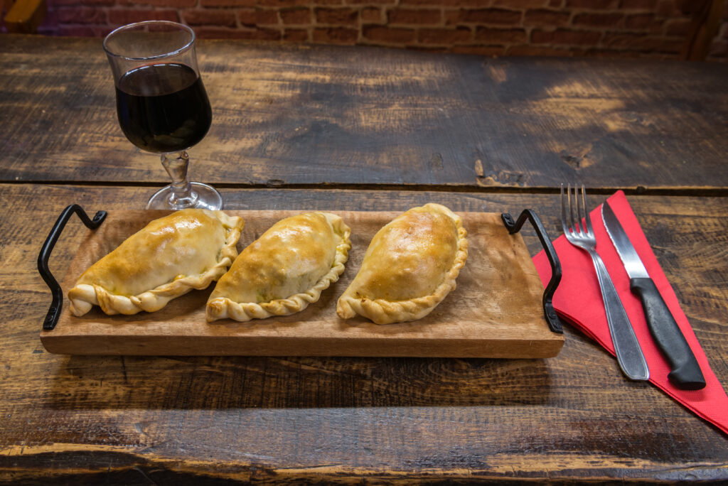 Empanadas tradicionales horneadas de Argentina y Uruguay, rellenas de carne de res, sobre un fondo de madera.